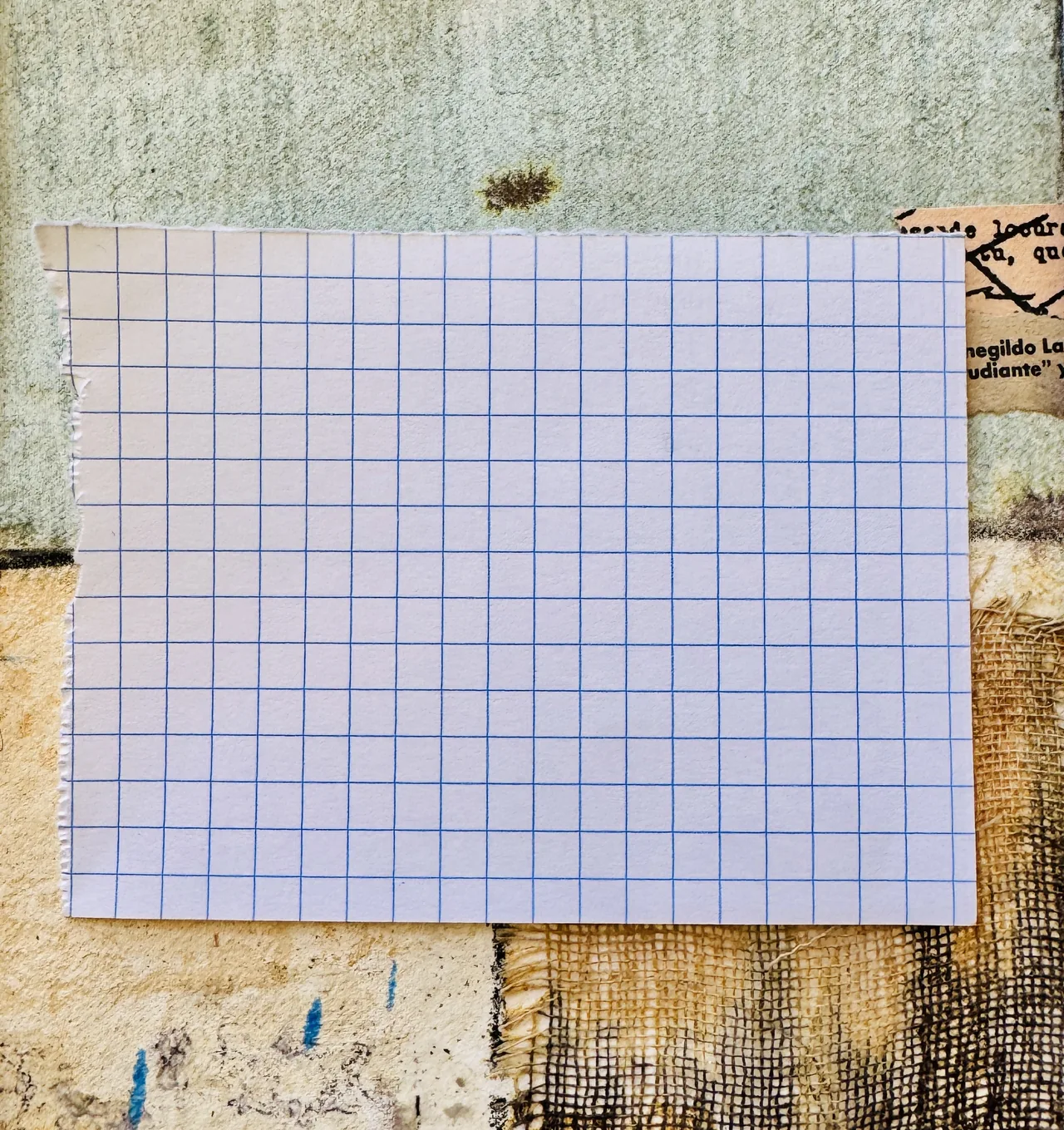 A hand-made collage: a sheet of pale graph paper pasted onto a textured ground of stained linen, sketchbook fragments and torn print. The working surface laid over the raw material.